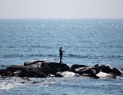A man fishing on the rocks.