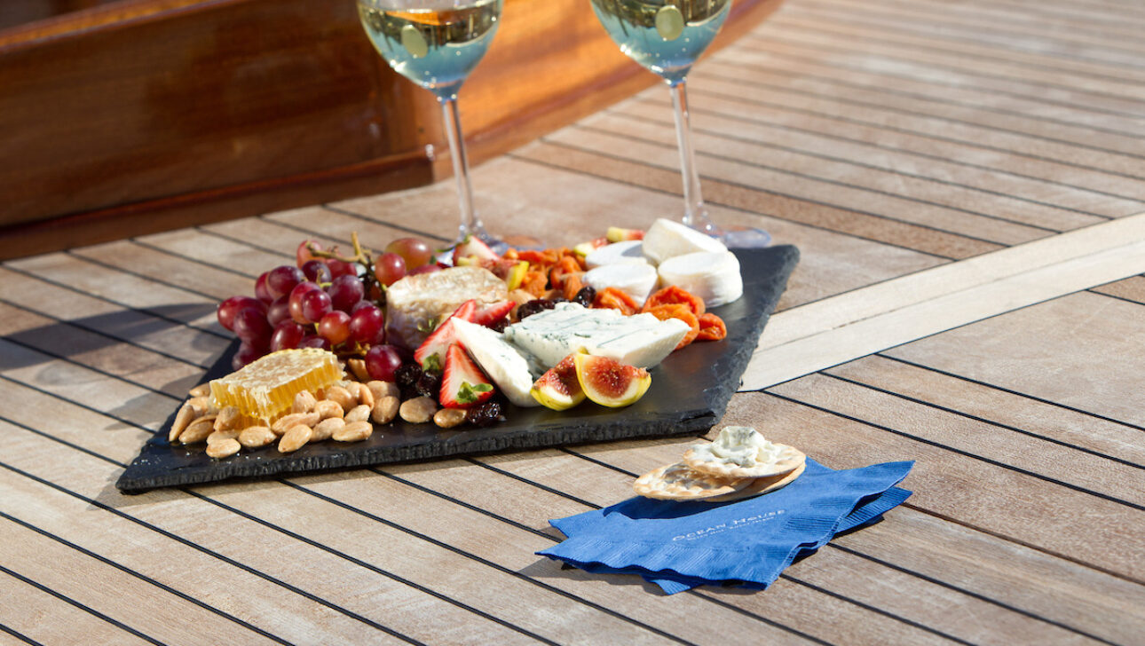 A charcuterie board along with two glasses of white wine.